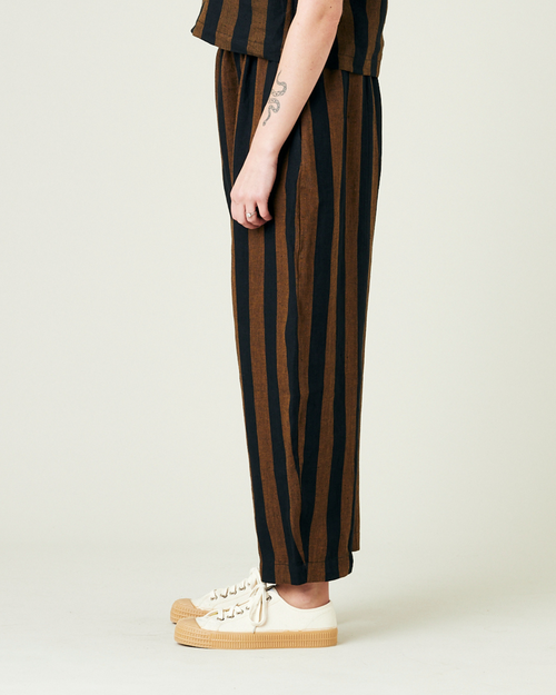 model wears rust stripe linen mabel trousers from the left