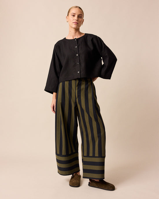 model wears blair olive and black stripe denim trousers left