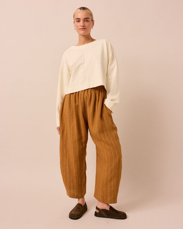 model wears honey pinstripe linen trousers right