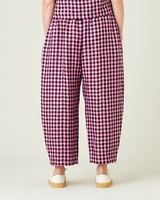 model wears pink and black gingham linen mabel trousers from the back