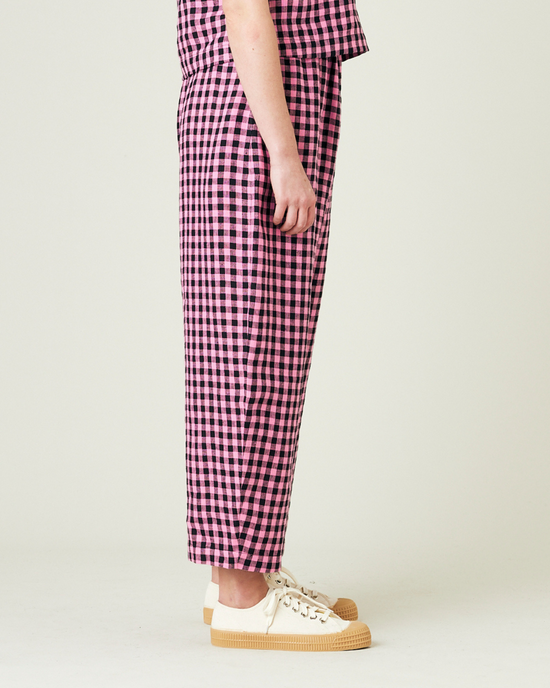 model wears pink and black gingham linen mabel trousers from the right