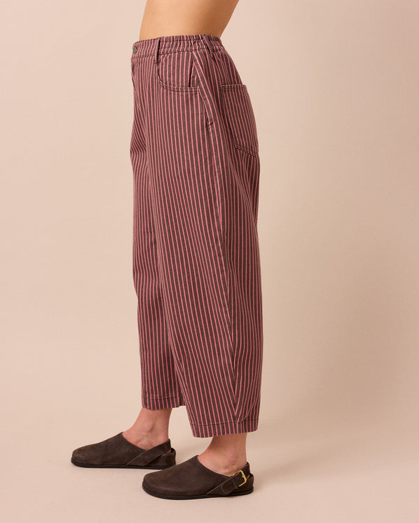 model wears remi pink and mocha stripe denim trousers left
