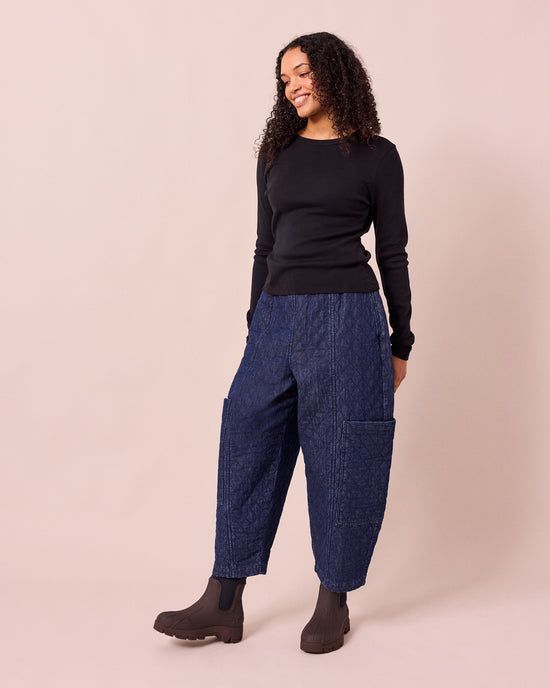 model wears amala dark blue quilted denim trousers left