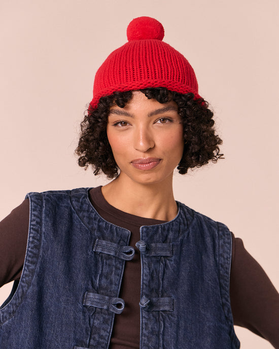 model wears poppy red knitted bobble hat