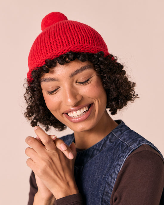 model wears poppy red knitted bobble hat