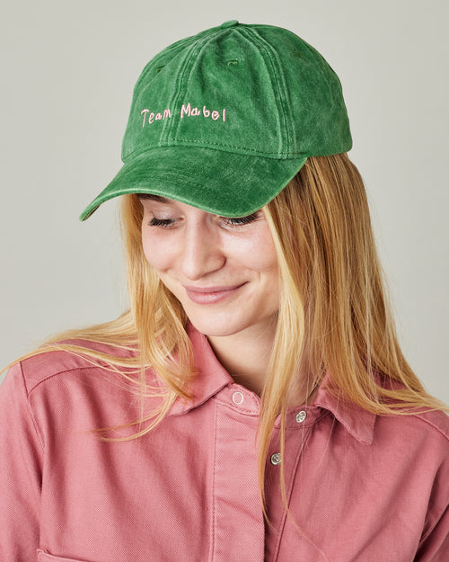 model wears green cord team mabel cap