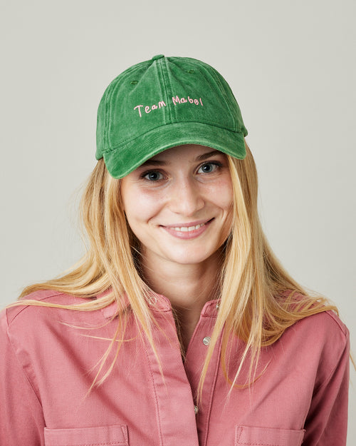 model wears green cord team mabel cap