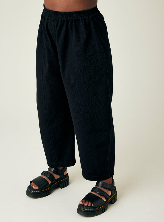 model wears black seersucker mabel trousers left