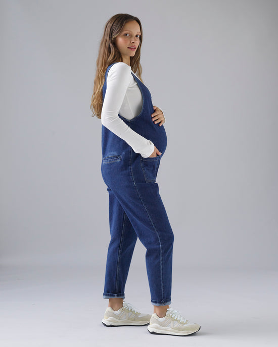 pregnant model wears mid blue denim lola jumpsuit