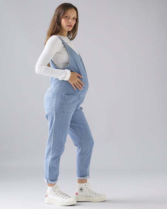 pregnant model wears light wash denim lola jumpsuit 