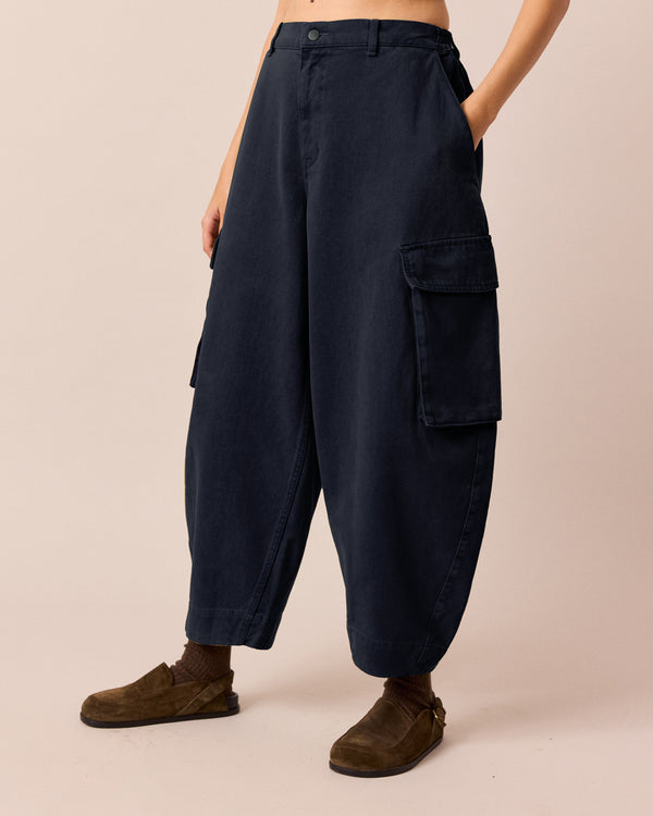 model wears claudie navy denim trousers left