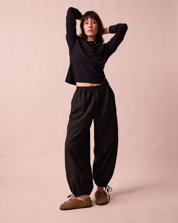 model wears codi black textured cotton trousers left