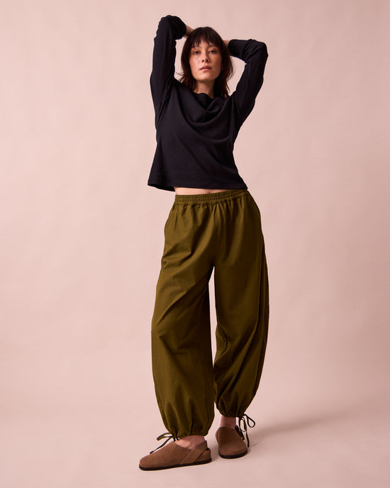 model wears codi dark olive textured cotton trousers left