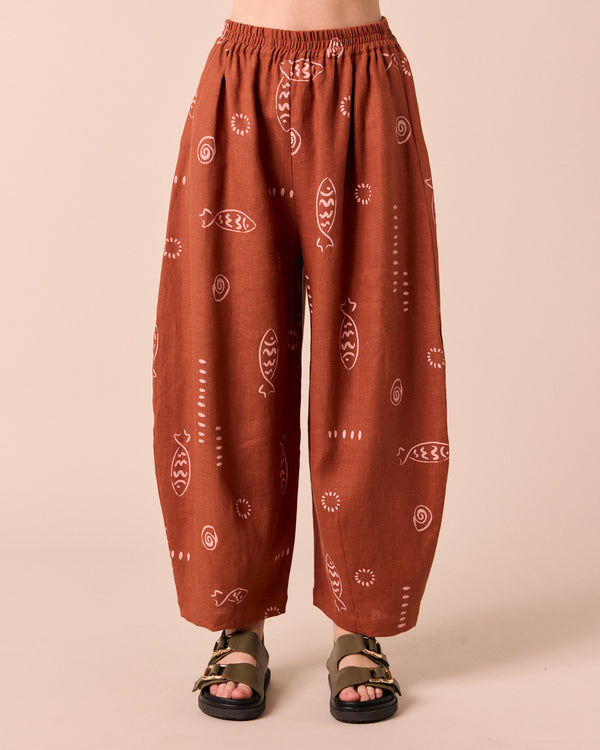 model wears daisy beachcomber print linen trousers.