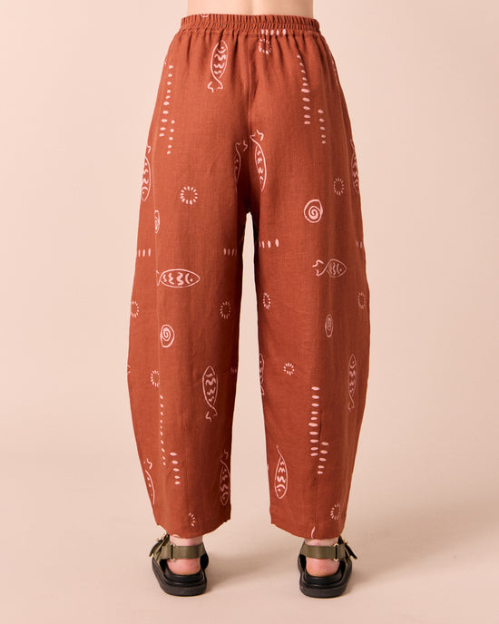 model wears daisy beachcomber print linen trousers.