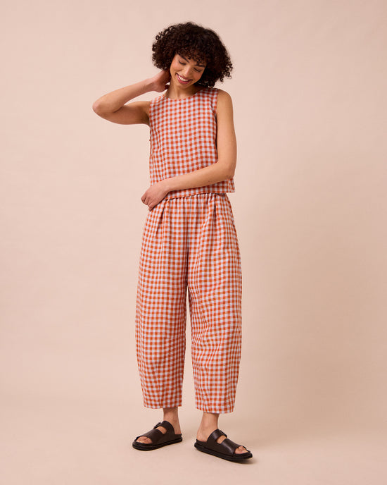 model wears daisy burnt orange gingham linen trousers left