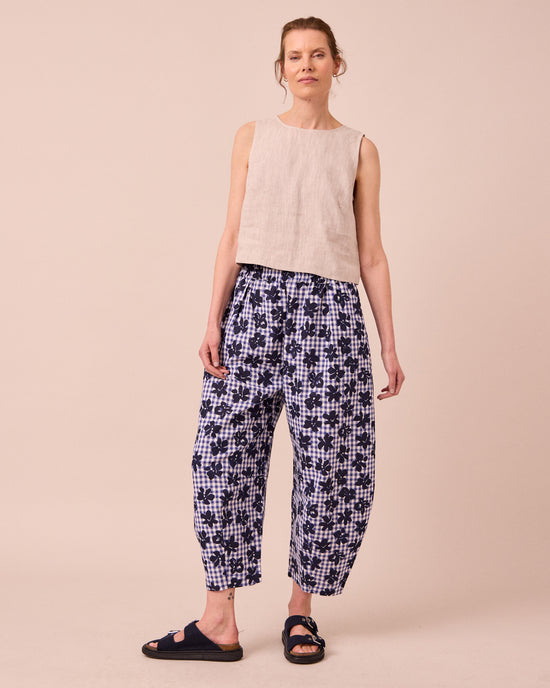 model wears daisy floral stamped gingham linen trousers left