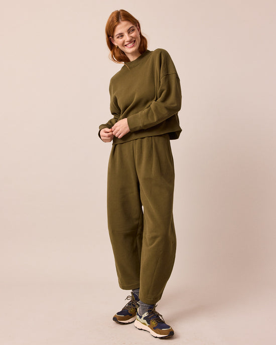 model wears daisy earth green jersey trousers right