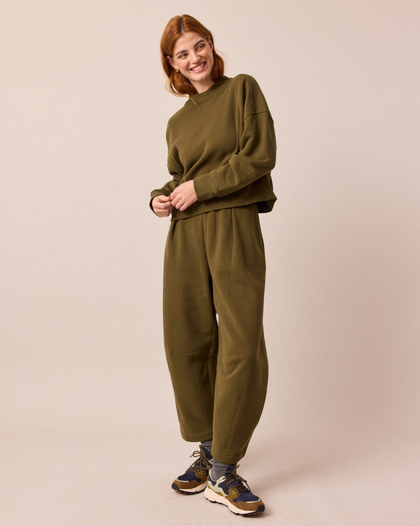 model wears daisy earth green jersey trousers right