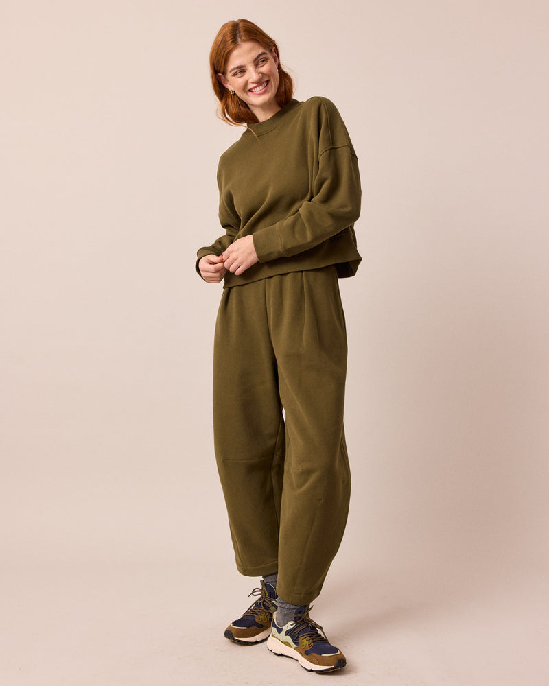 model wears daisy earth green jersey trousers right