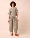 model wears daisy olive gingham linen trousers left