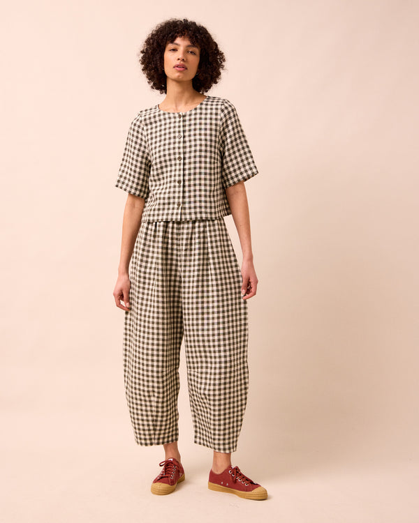 model wears daisy olive gingham linen trousers left