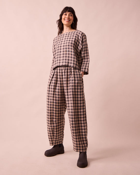 model wears daisy stone gingham linen trousers left