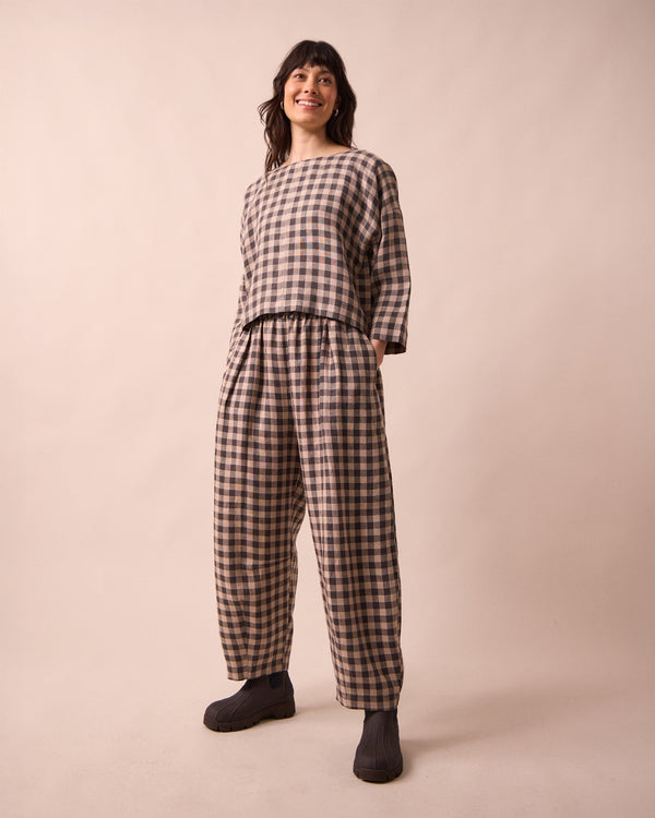 model wears daisy stone gingham linen trousers left