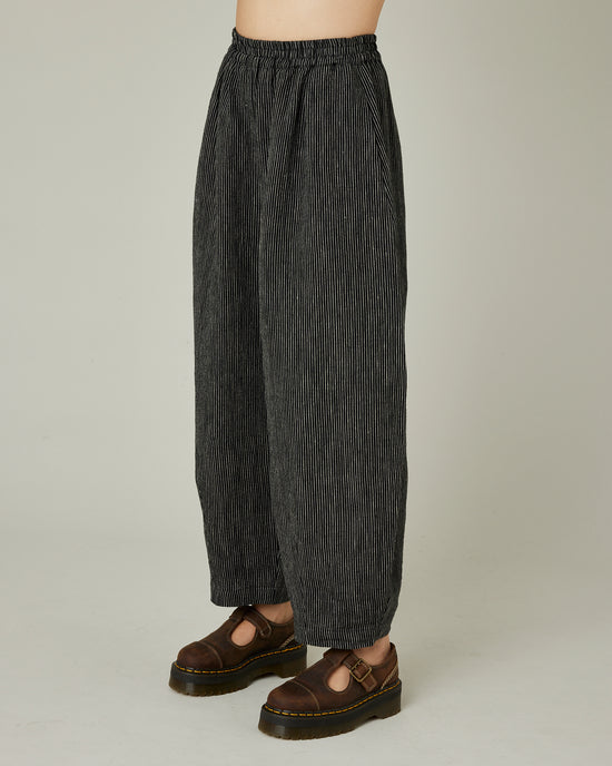 model wears black and ecru pencil stripe daisy trousers left