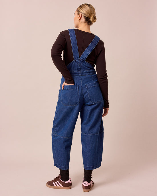 model wears gwynne mid blue denim dungerees