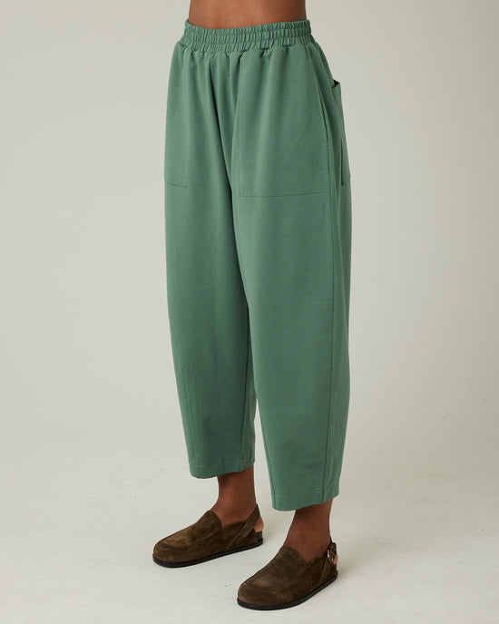 model wears dusty green huxley jersey trousers left