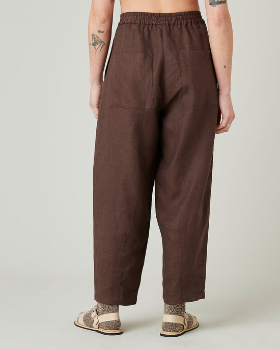 model wears brown huxley linen trousers back