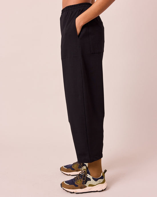 model wears huxley black jersey trousers left