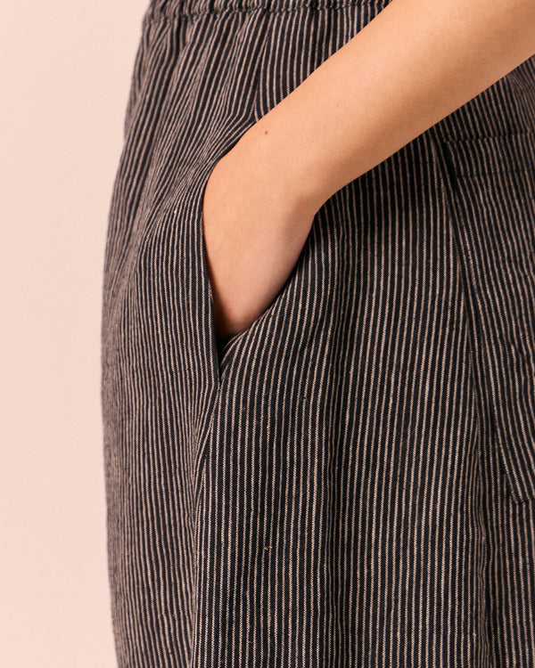 model wears logan black and ecru pencil stripe linen trousers. 