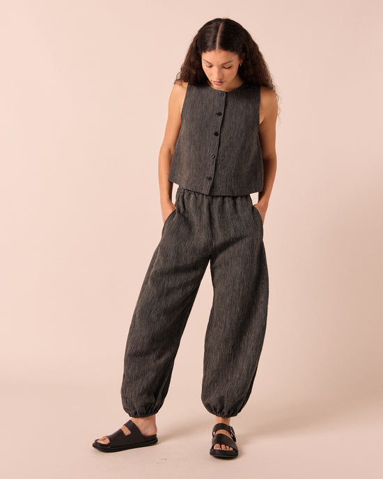 model wears logan black and ecru pencil stripe linen trousers. 