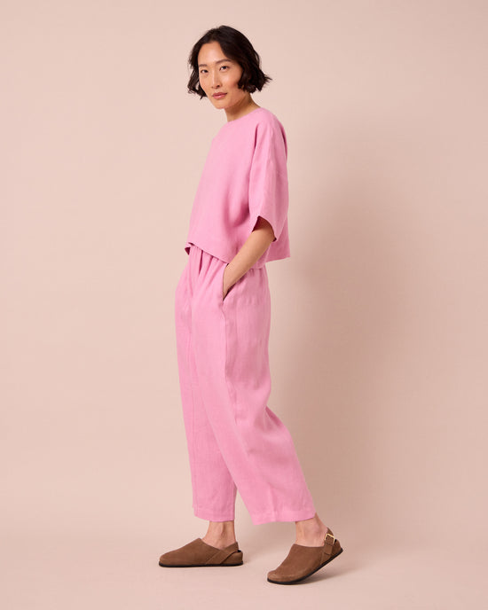 model wears mabel rose pink linen trousers left