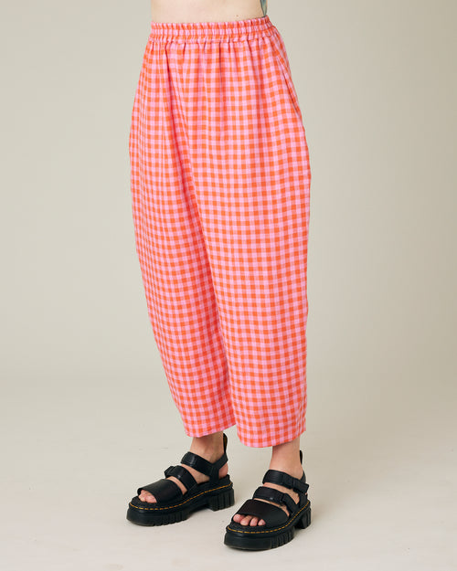 model wears longer length tomato and pink check linen mabel trousers left