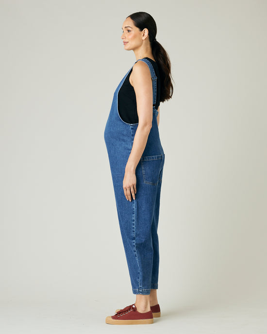 pregnant model wears mid blue denim ottie jumpsuit