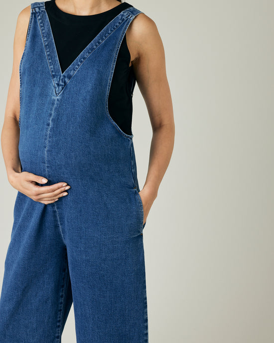 pregnant model wears mid blue denim ottie jumpsuit