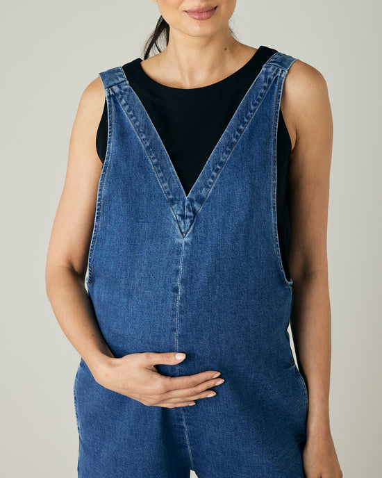 pregnant model wears mid blue denim ottie jumpsuit