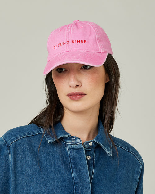 model wears pink beyond niner cap