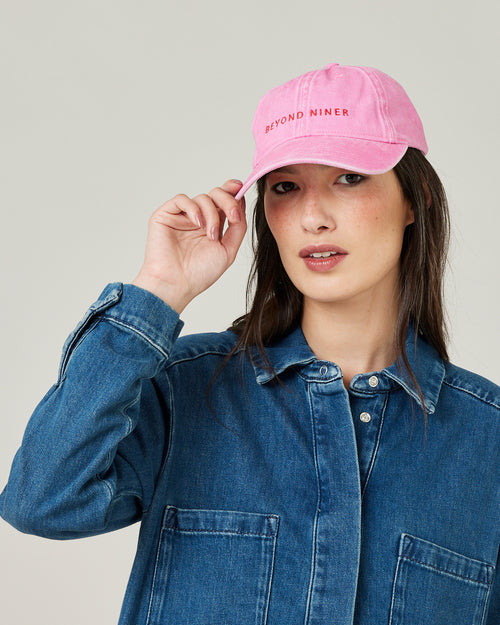 model wears pink beyond niner cap