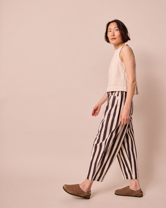 model wears remi ecru and chocolate denim jeans right