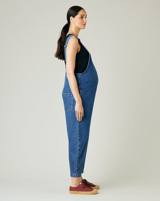 pregnant model wears mid blue denim ottie jumpsuit