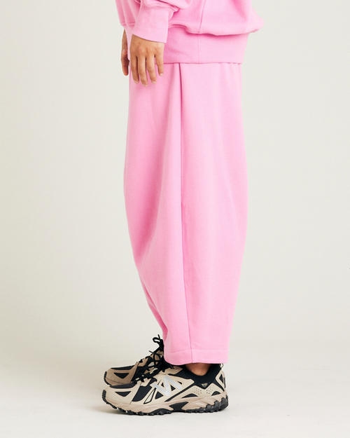 model wears pink daisy jersey trousers left