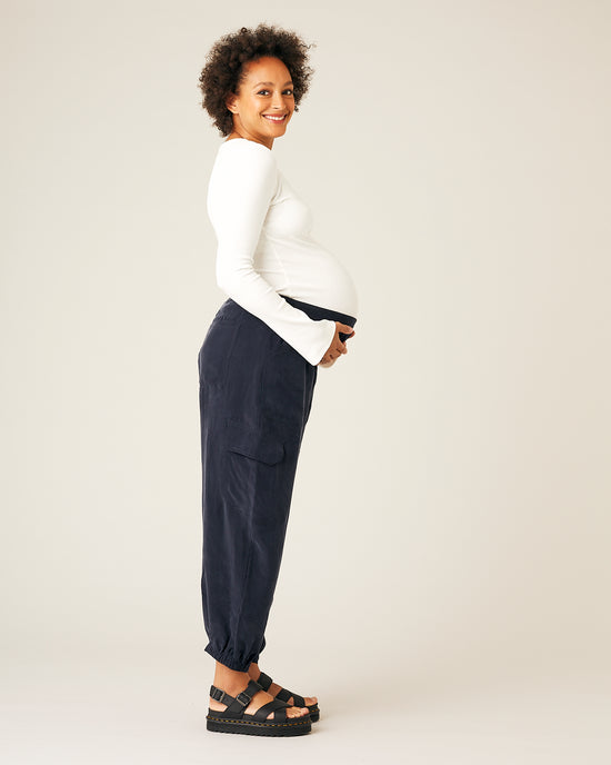 pregnant model wears navy sylvie cupro trousers