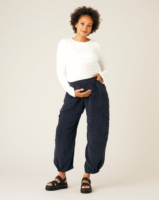 pregnant model wears navy sylvie cupro trousers